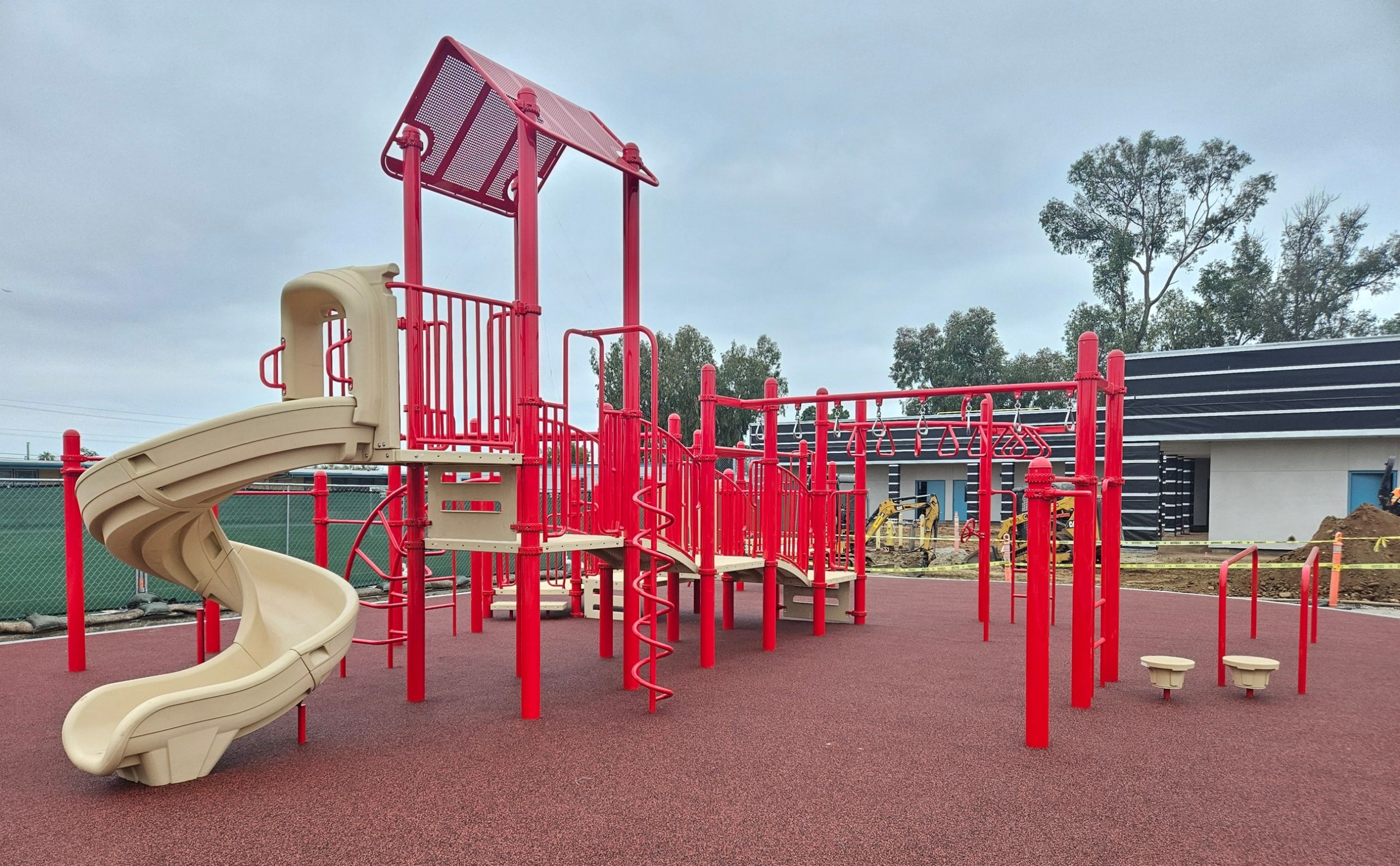 DSA playground installation at Oak Park Elementary showing a red playground with red PIP surfacing, slides, and monkey bar climbers