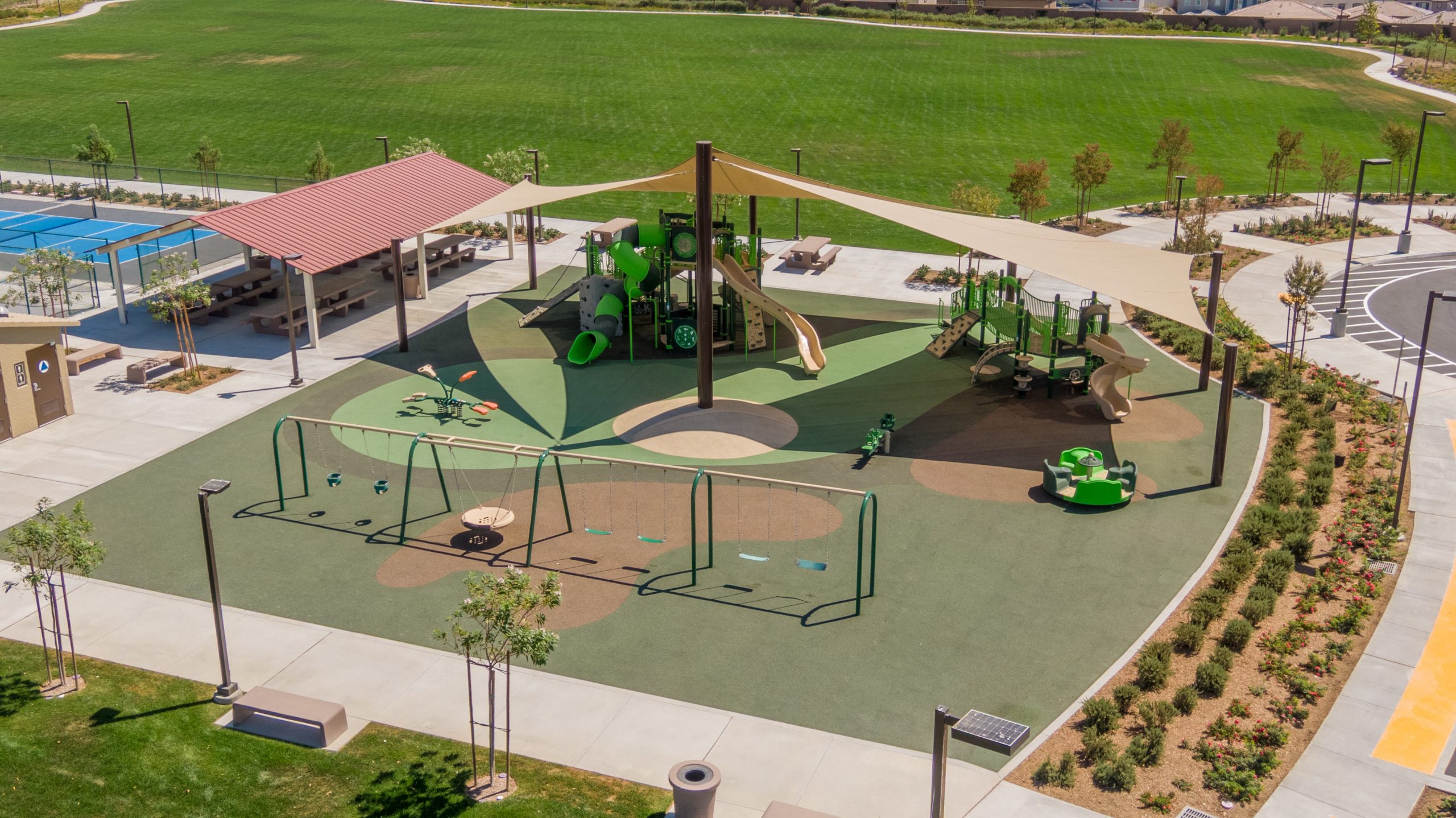 Panoramic perspective of Fairway Canyon Park’s commercial playground installation featuring play structures, slides, swings, and shade elements.