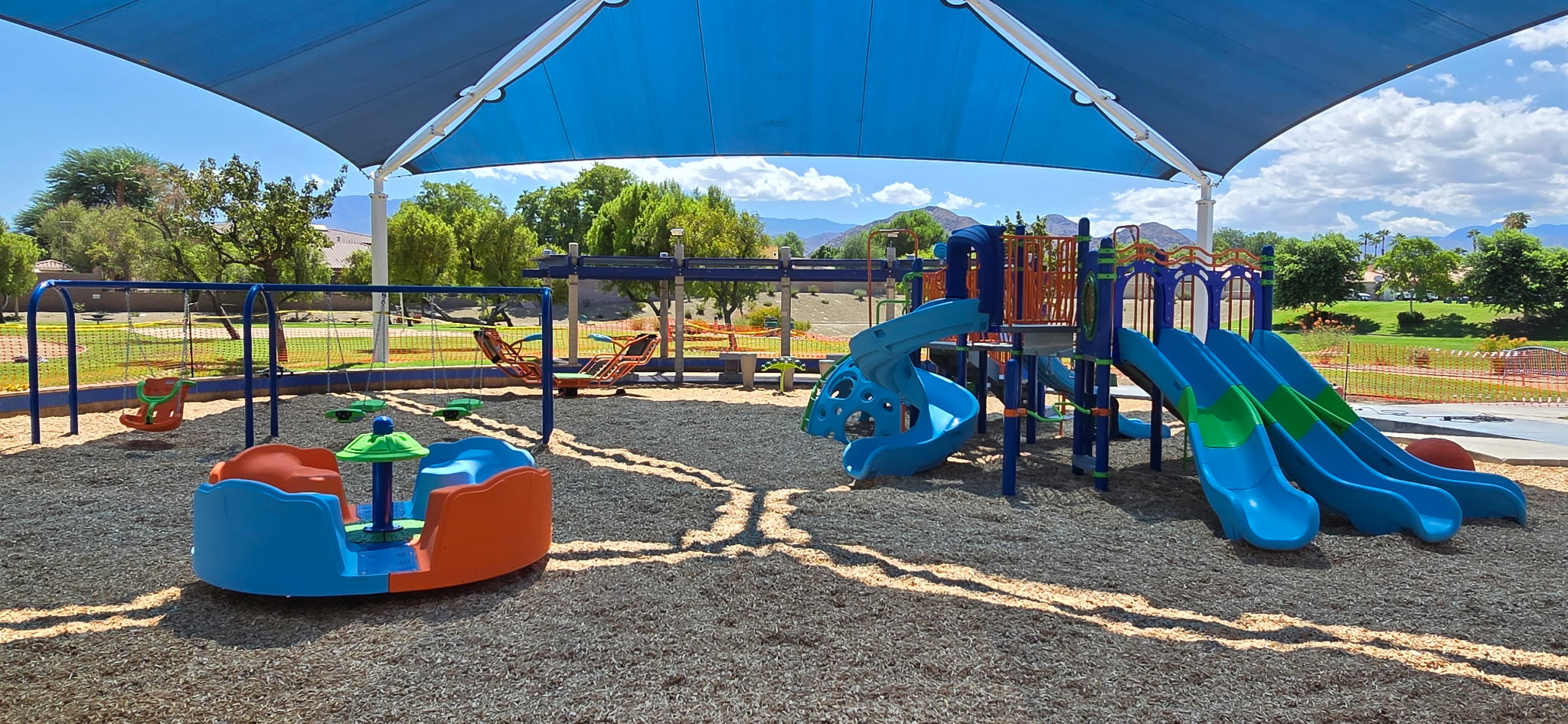 Children’s swings under a shade structure at Adams Park in La Quinta, designed for safe and inclusive play by Pacific Play Systems.